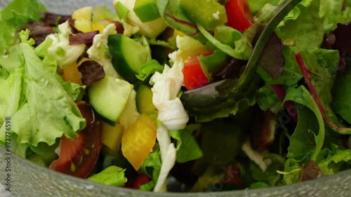 Women's hands mix salad with tomato tomato mozzarella vegetables and arugula in a large bowl for an easy diet lunch or dinner, a healthy balanced meal