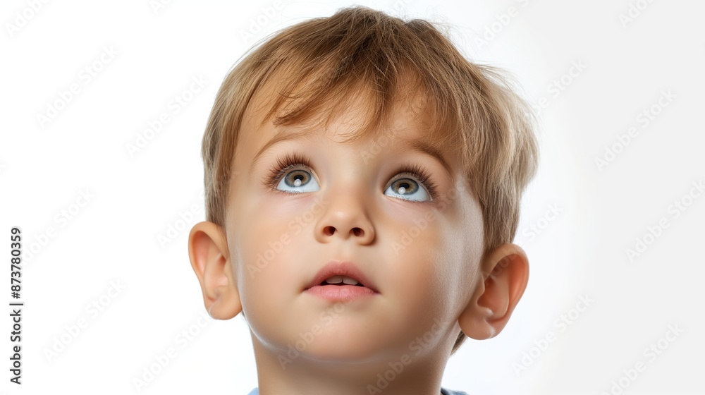 A young boy with brown hair and blue eyes is looking up at the camera. He has a smile on his face and his eyes are wide open. Concept of curiosity and wonder A young boy with brown hair and blue eyes is looking up at the camera. He has a smile on his face and his eyes are wide open. Concept of curiosity and wonder
