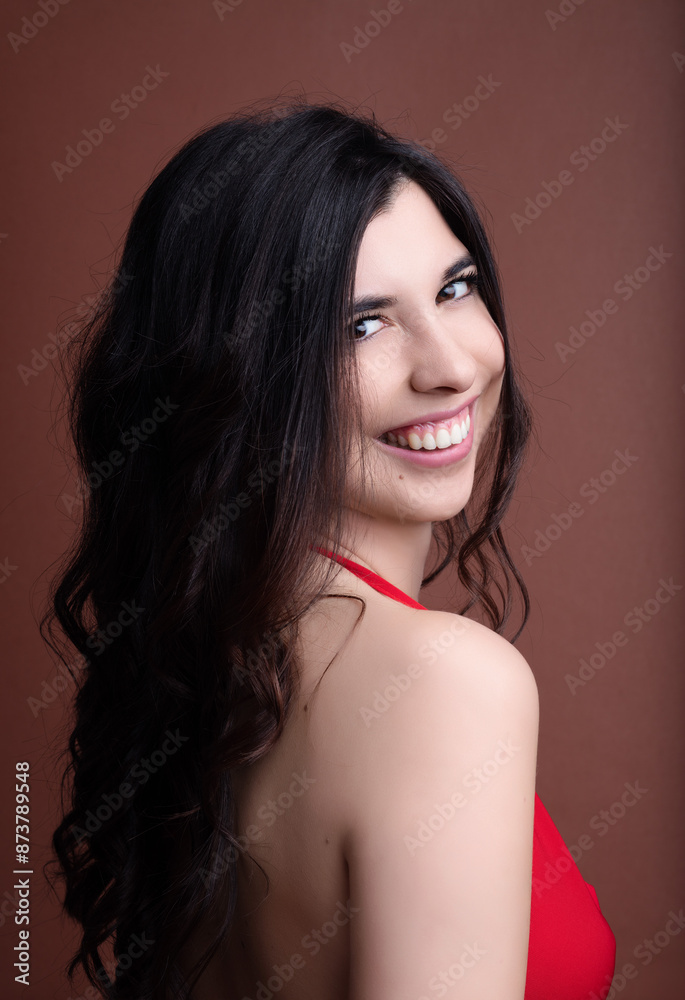 Beautiful young woman with long black hair smiling over shoulder Beautiful young woman with long black hair smiling over shoulder