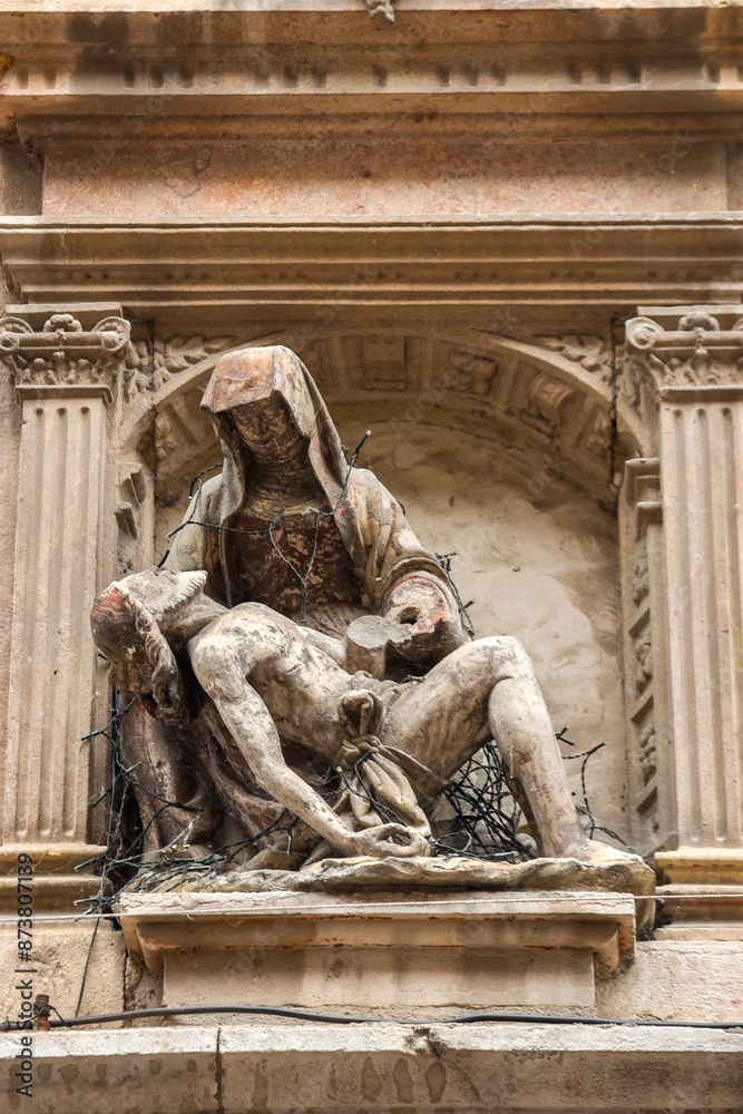 small weathered and deteriorated sculpture of the virgin Mary holding Jesus body