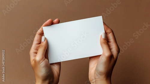 Mockup booklet presentation: Woman's hands hold blank white flyer on brown background 