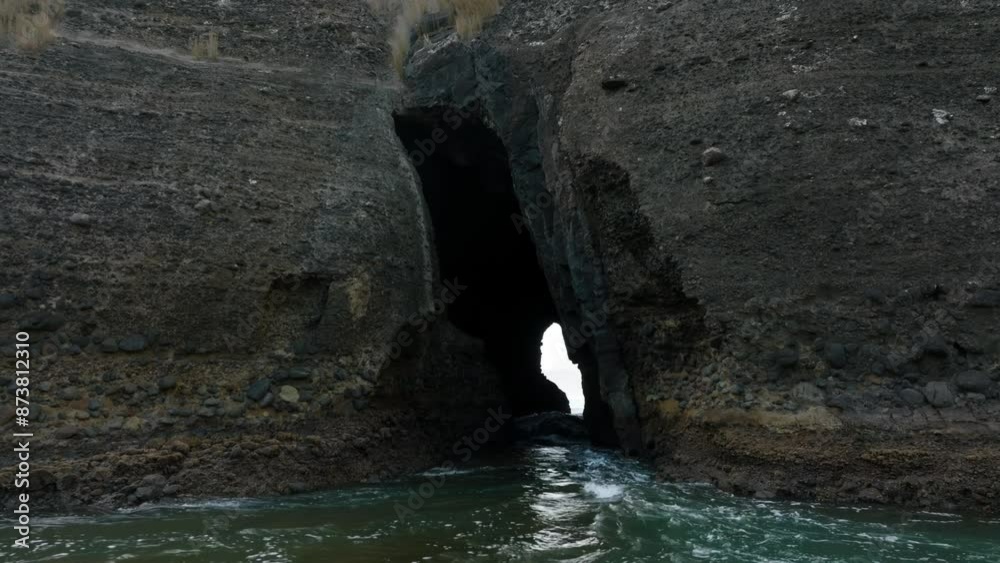 Keyhole cavern going into a cliff with tidal waves coming through it. Piha, Auckland, New Zealand.