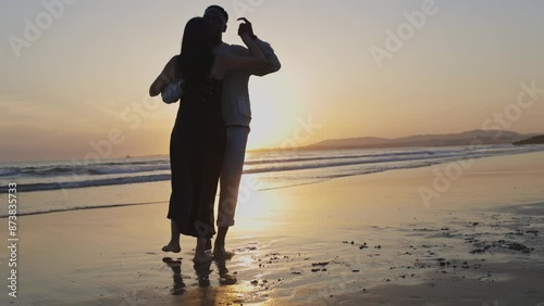 A couple is kissing on the beach at sunset