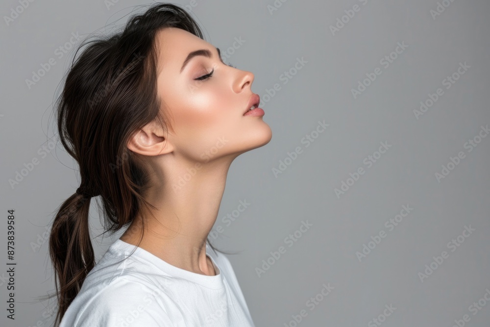 Side Profile of Chic Brunette Woman in White T-shirt, Curious and Confident, with Copy Space on Grey Background Side Profile of Chic Brunette Woman in White T-shirt, Curious and Confident, with Copy Space on Grey Background