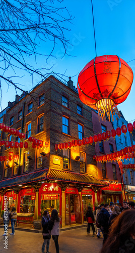 Canvas Print Tourists strolling and chatting on a street corner in Soho's Chinatown in front of a chio restaurant and red Chinese lanterns hanging on the walls at dusk