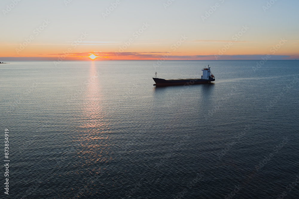 Unloaded container ship in the Baltic sea st sunrise or sunset, photo view from a drone.