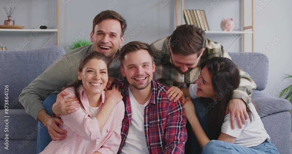 Happy friends come together for joint photo with smiles on their faces showing closeness and joy. Group of friends laughs and poses on sofa in living room. Concept of friendship, fun and togetherness. Happy friends come together for joint photo with smiles on their faces showing closeness and joy. Group of friends laughs and poses on sofa in living room. Concept of friendship, fun and togetherness.