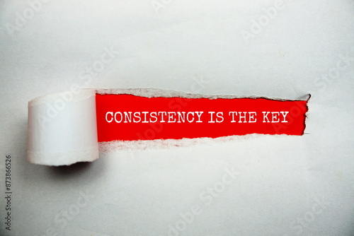 Consistency Is The Key message written on red paper with torn paper background