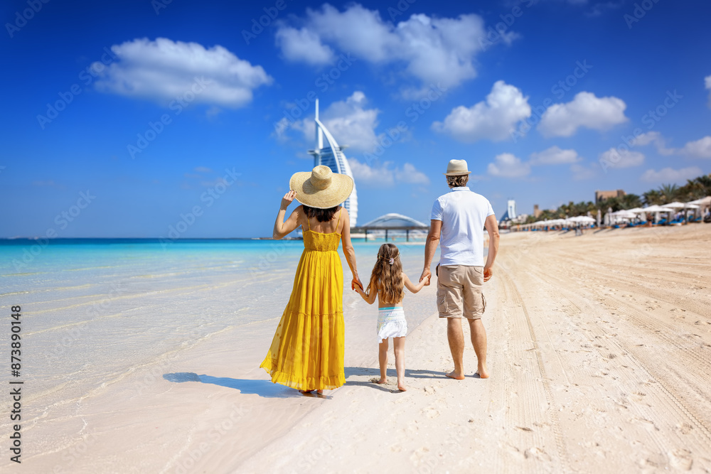 A tourist family on summer holiday time walks down a beautiful city beach in Dubai, United Arab Emirates