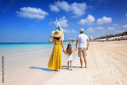 Obraz na płótnie A tourist family on summer holiday time walks down a beautiful city beach in Dubai, United Arab Emirates w salonie
