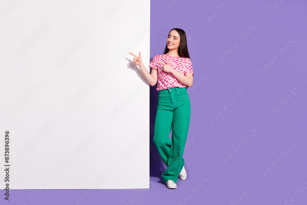 Full length photo of lovely young lady point look white wall empty space dressed stylish pink garment isolated on violet color background Full length photo of lovely young lady point look white wall empty space dressed stylish pink garment isolated on violet color background