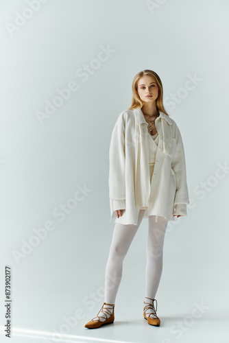 A young woman stands confidently in a white outfit against a plain background.