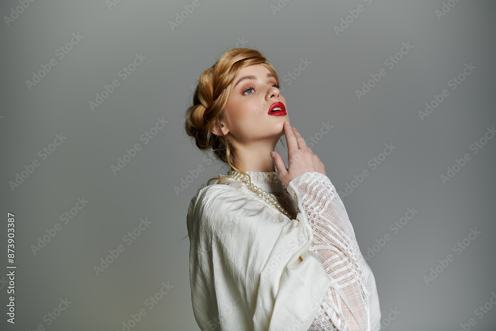 A woman in a white dress and pearl necklace gazes upwards, her hand gently touching her chin. A woman in a white dress and pearl necklace gazes upwards, her hand gently touching her chin.