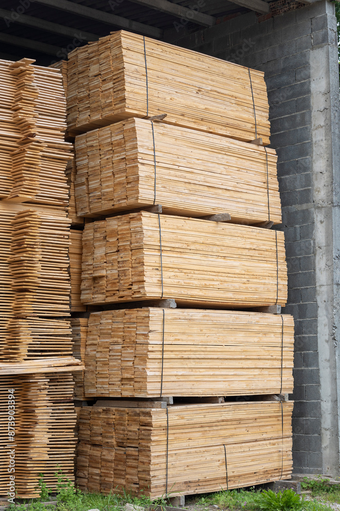 Large stacks of neatly arranged wooden boards are stacked outdoors on a bright, sunny day, likely for construction or woodworking purposes, against a natural backdrop. Large stacks of neatly arranged wooden boards are stacked outdoors on a bright, sunny day, likely for construction or woodworking purposes, against a natural backdrop.