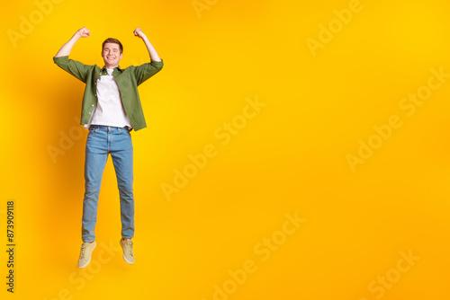 Photo of overjoyed glad cheerful man wear stylish clothes hands fists empty space isolated on vivid yellow color background © deagreez