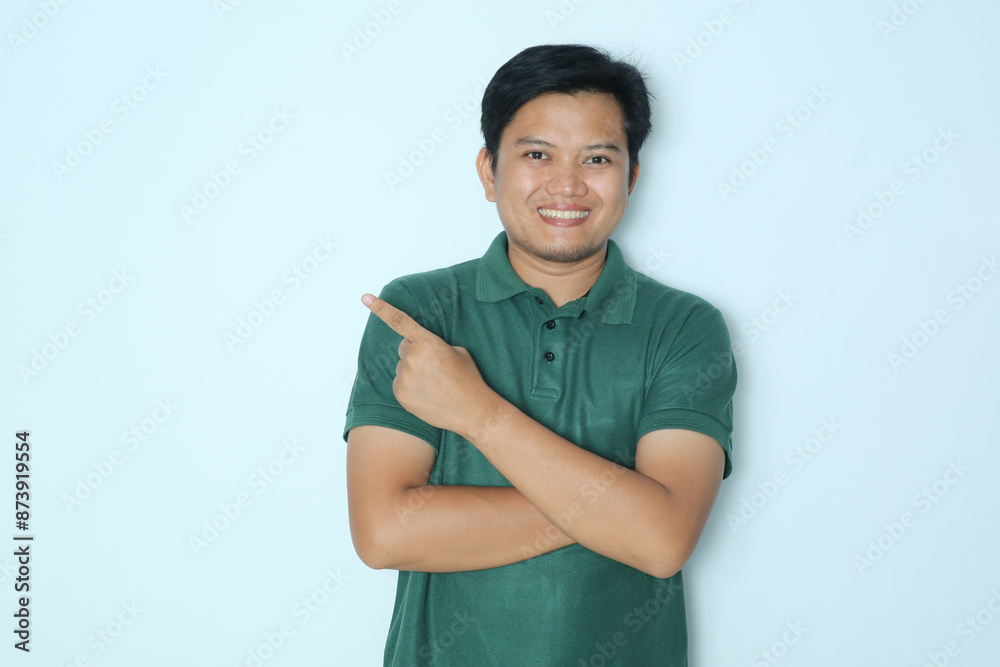 Young Asian man pointing finger to the right with smiling face. Wearing a green t-shirt Young Asian man pointing finger to the right with smiling face. Wearing a green t-shirt