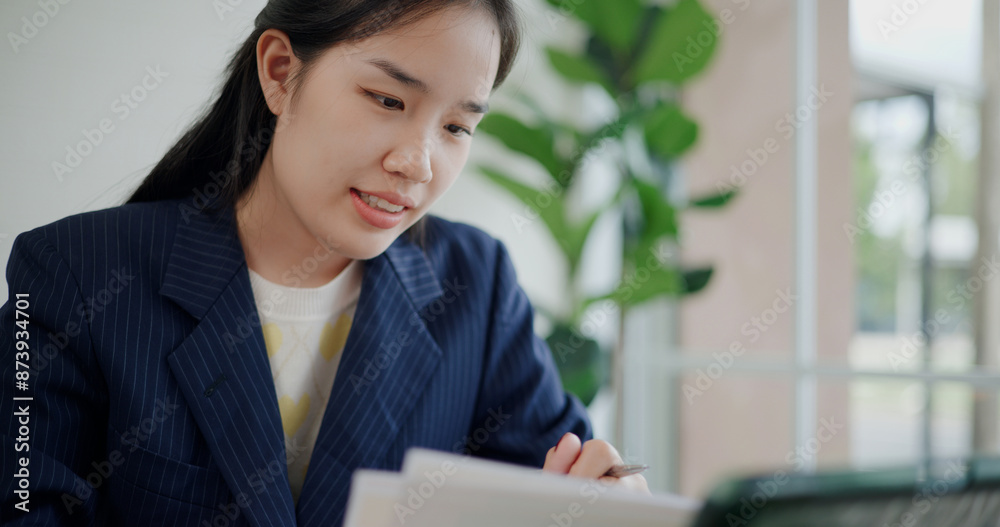 Fototapeta premium Portrait of Asian businesswoman in suit use digital tablet for work and analyze documents in small coffee shop. Work from anywhere, Remote working