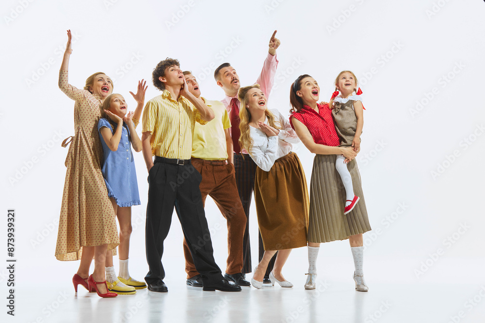 Fototapeta premium A group of people in vintage attire pointing and looking upwards with shock and excitement, isolated on white background. Announcement, event, discovery, news. Opening