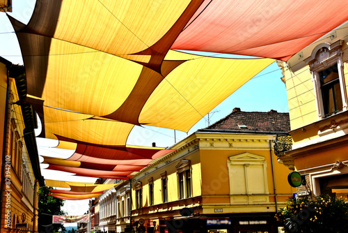 canvas patio awning. colorful tightly weaved sun shade sail. UV and sun protection fabric suspended from exterior walls. urban street in old city. holiday concept.