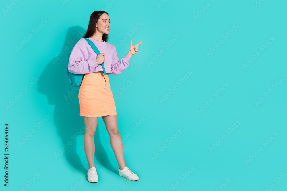 Full body photo of pretty young girl look point empty space wear trendy violet outfit isolated on cyan color background Full body photo of pretty young girl look point empty space wear trendy violet outfit isolated on cyan color background