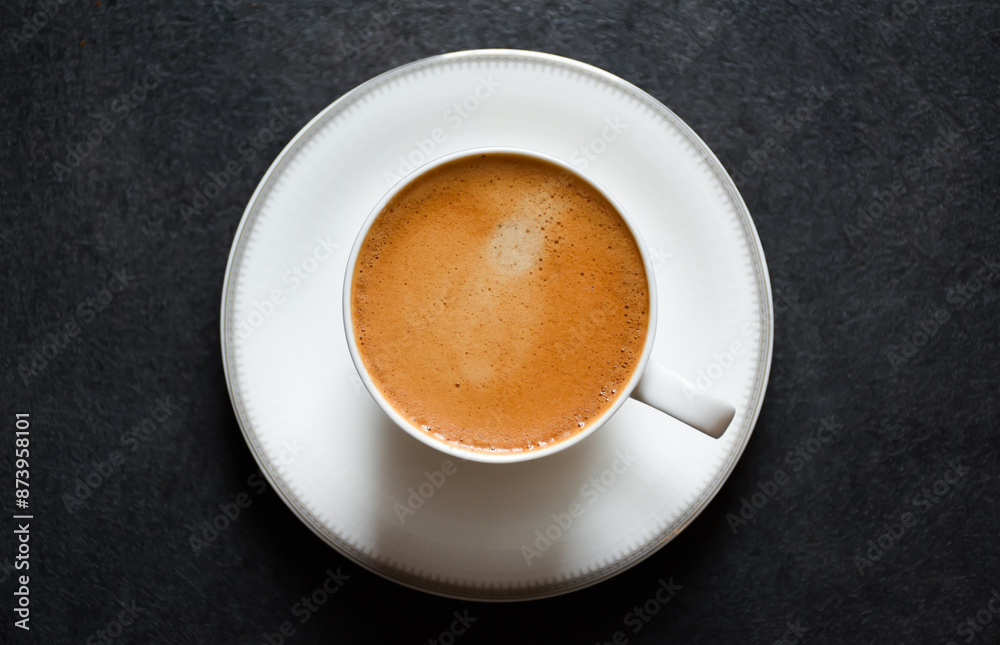 Top view of morning espresso coffee or black coffee in a white glass cup on a black table background 2024. Beautiful coffee cup with foam of Americano on black background. Top view of morning espresso coffee or black coffee in a white glass cup on a black table background 2024. Beautiful coffee cup with foam of Americano on black background.