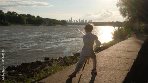 Silhouette of a boy in a Japanese kimono with a sword against the background of evening Warsaw. Slow motion