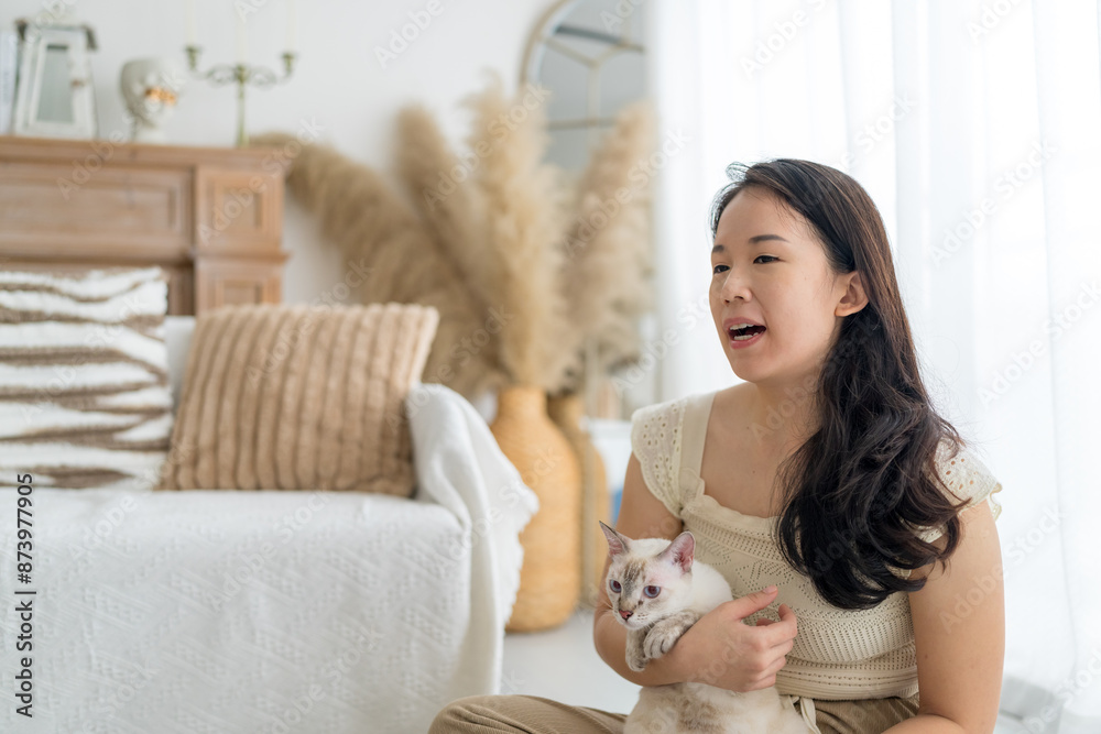 A Chinese Malaysian woman in her 20s wearing casual, warm-colored clothing, playing with a cat in her home in Malaysia A Chinese Malaysian woman in her 20s wearing casual, warm-colored clothing, playing with a cat in her home in Malaysia