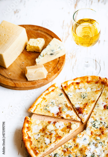 Pizza quattro formaggi on a wooden board .four cheese pizza and fresh ingredients for a four cheeses Italian pizza on a white wooden desk . photo