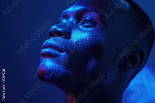 Blue Text. Young Ethnic Man Poses in Dark Studio Illuminated by Projector Glow