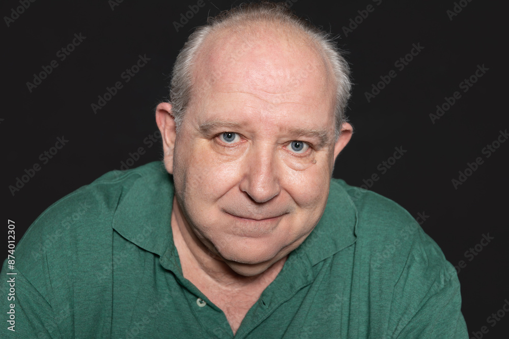 Close-up portrait of a 60 years old man with white hair, dressed in a green polo shirt, looking at camera with his blue eyes and kind expression. Concept of aging Close-up portrait of a 60 years old man with white hair, dressed in a green polo shirt, looking at camera with his blue eyes and kind expression. Concept of aging