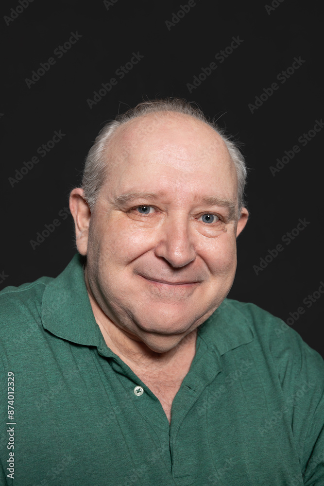 Portrait of a sexagenarian man dressed in a green polo shirt, with gray hair and blue eyes, looking at smiling camera with relaxed and happy expression. Concept of aging Portrait of a sexagenarian man dressed in a green polo shirt, with gray hair and blue eyes, looking at smiling camera with relaxed and happy expression. Concept of aging