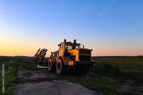 Cultivator on agricultural field at golden hour. Machine in field at sunset.