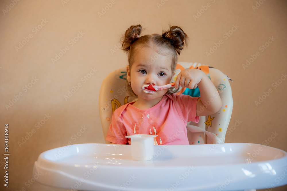 A little girl is sitting on a high chair eating at home A little girl is sitting on a high chair eating at home
