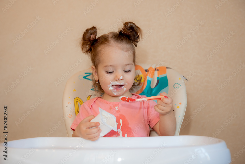 A little girl is sitting on a high chair eating at home A little girl is sitting on a high chair eating at home