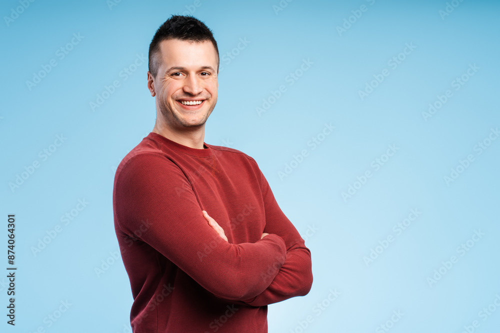 Happy smiling man standing with arms crossed, isolated on blue background Happy smiling man standing with arms crossed, isolated on blue background