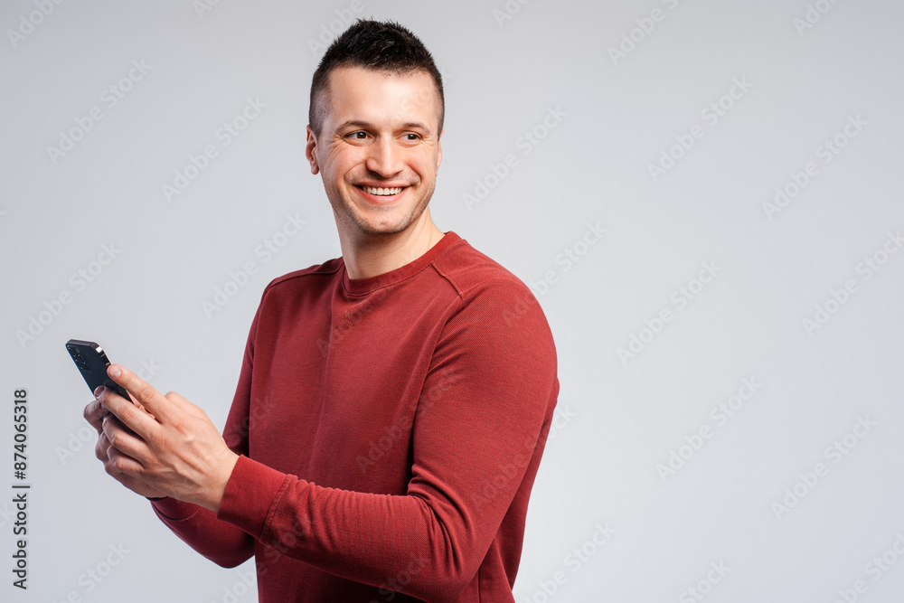Smiling, attractive middle aged man wearing stylish red sweater, holding mobile phone Smiling, attractive middle aged man wearing stylish red sweater, holding mobile phone