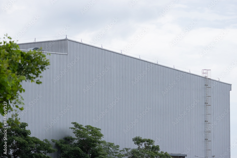 A large building with a grey roof and a ladder on the side A large building with a grey roof and a ladder on the side