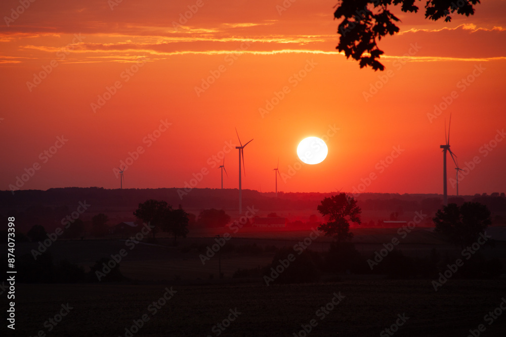 Fototapeta premium red sunset over a field of windmills