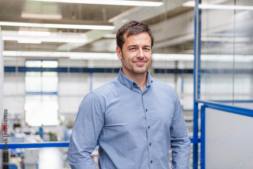 Smiling businessman standing in factory Smiling businessman standing in factory