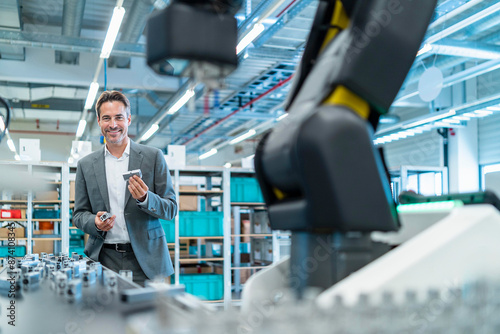 Smiling engineer holding manufactured parts at factory