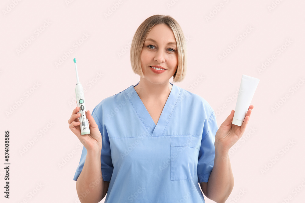 Female dentist with tooth brush and paste on pink background Female dentist with tooth brush and paste on pink background