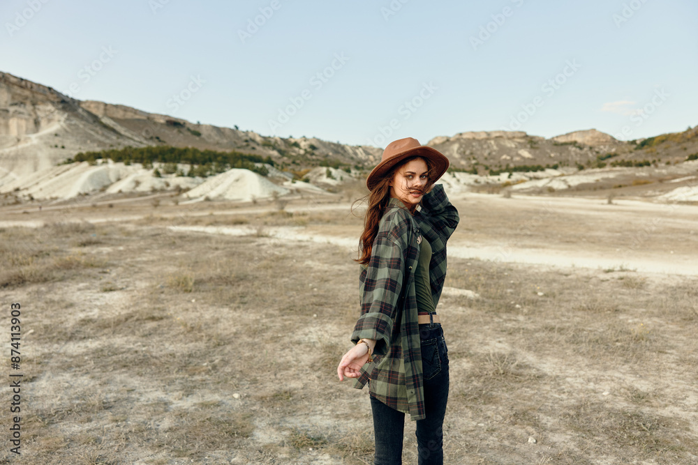 Naklejka premium Serenity in the countryside woman in hat and plaid shirt standing in field on a sunny day