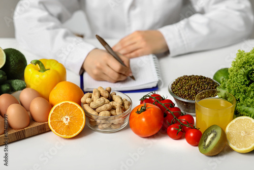 Young female nutritionist with healthy food writing diet plan in office, closeup