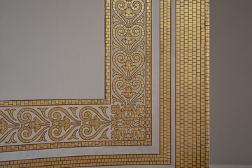 A corner detail of gold mosaic tilework with ornate patterns
