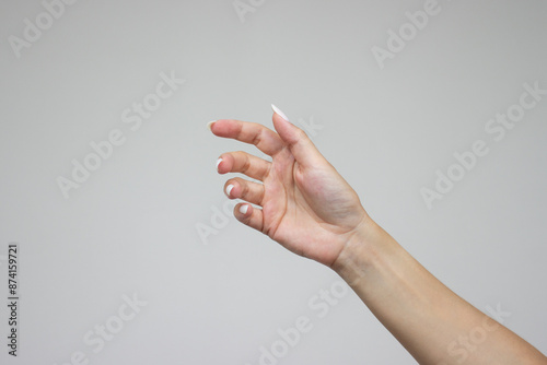 A woman's hand is open and holding something like a bottle. Gesture isolated on gray background. The girl gives some object. Product presentation concept or mockup with copy space. Advertising