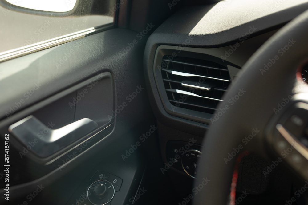 The interior of a car with a door handle and an air vent visible The interior of a car with a door handle and an air vent visible