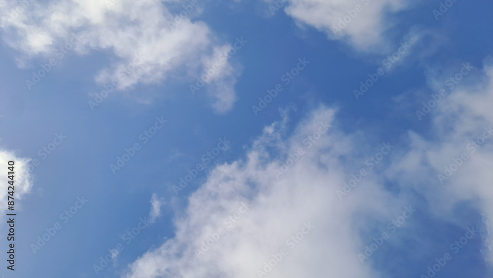 Fototapeta premium White clouds slowly forming in a calm blue sky