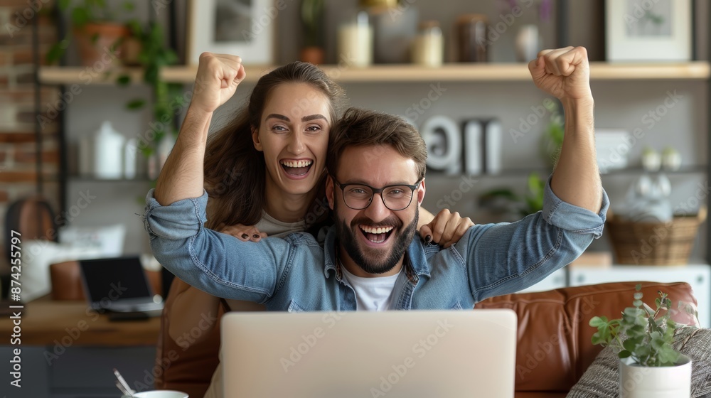 Happy couple celebrating success while looking at a laptop screen in a cozy home environment, expressing excitement and joy. Happy couple celebrating success while looking at a laptop screen in a cozy home environment, expressing excitement and joy.