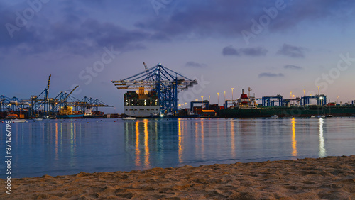 Bild auf Leinwand Bustling port scene at night featuring cargo ships, illuminated cranes, and thei