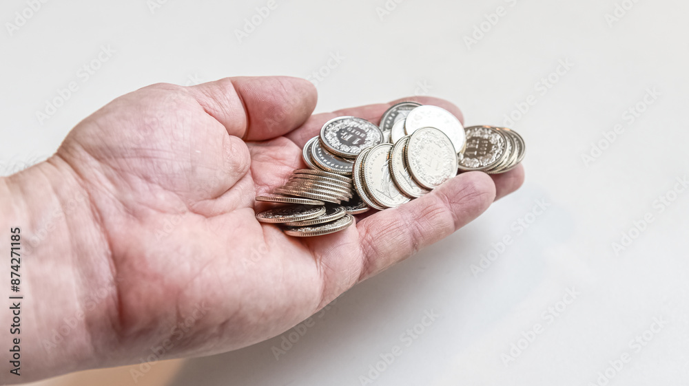 hand holding in the palm a stack of coins spread on white background